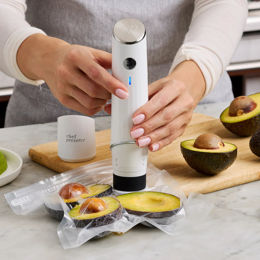 Hands using Chef Preserve compact vacuum sealer to preserve fresh avocados in vacuum-sealed bag